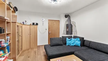 Wohnzimmer mit Kaminofen, Ecksofa und Holzmöbeln, das eine gemütliche Atmosphäre schafft.