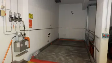 Fahrzeuglift in einer Tiefgarage mit Steuerungselementen und Nummerierung an der Wand.
