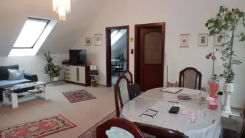 Geräumiger Wohn-Essbereich im Dachgeschoss mit Teppichboden, Dachfenster und Zugang zu weiteren Räumen.