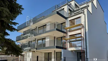 Modernes Mehrfamilienhaus mit mehreren Balkonen und Außentreppen, noch im Bau befindlich.