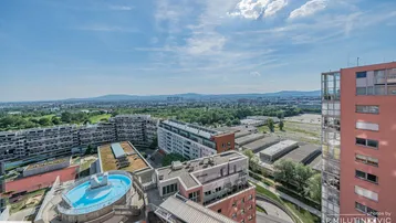 Weitläufige Stadtansicht von oben mit Blick auf Gebäude, Berge und einen Dachpool.