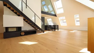 Helles, offenes Dachgeschoss mit Holzparkettboden, moderner Treppe und vielen Dachfenstern.