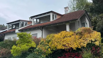 Ansicht des Hauses mit mehreren Balkonen und üppiger Herbstbepflanzung im Gartenbereich.
