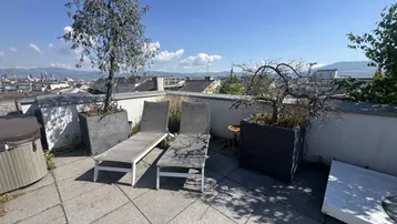 Sonniger Dachgarten mit Liegestühlen, Pflanzen und einem Whirlpool, ideal zum Entspannen.