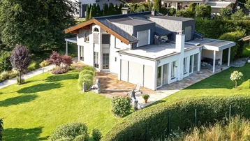 Modernes Einfamilienhaus mit gepflegtem Garten, Terrasse und Carport in sonniger Hanglage.