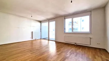 Helles Wohnzimmer mit Parkettboden, großen Fenstern und Zugang zum Balkon.