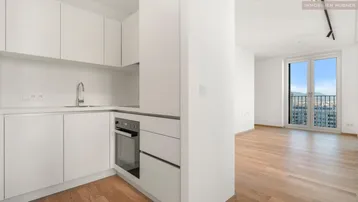 Moderne Einbauküche mit weißen Schränken und integriertem Ofen, offen zum hellen Wohnbereich mit Stadtblick.