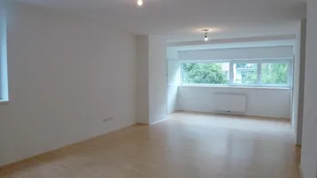 Helles, leeres Zimmer mit Parkettboden und großen Fenstern, bereit zur individuellen Gestaltung.