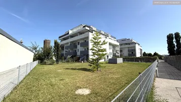 Modernes Mehrfamilienhaus mit gepflegter Grünfläche und klaren architektonischen Linien.