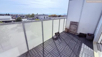 Geräumiger Balkon mit modernen Bodenfliesen und Blick auf die Umgebung.