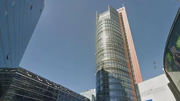 Moderne Hochhäuser mit Glasfassaden und einer belebten städtischen Umgebung unter klarem Himmel.