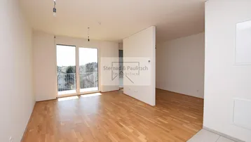 Helles, leeres Zimmer mit Parkettboden und Zugang zum Balkon, ideal für Wohn- oder Essbereich.