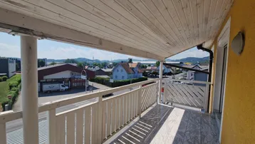 Geräumiger Balkon mit Holzdach, Fliesenboden und weitem Blick über die Nachbarschaft.