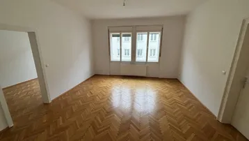 Geräumiges Zimmer mit Fischgrätparkett und hellen Wänden, bereit zur individuellen Gestaltung.
