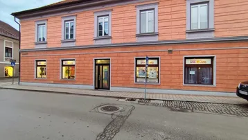 Historisches Gebäude mit einer pfirsichfarbenen Fassade und großen Fenstern, die auf eine ruhige Straße blicken.