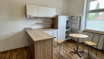 Helle Küche mit Laminatboden, integrierter Küchenzeile und Essbereich am Fenster.