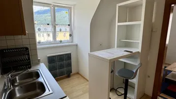 Kleine Küche mit Spülbecken, Frühstücksbar und einem Fenster mit Bergblick.