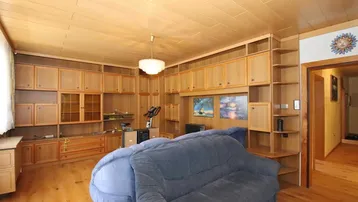 Helles Wohnzimmer mit umfangreichen Holzmöbeln, Holzdecke und Parkettboden, ideal für gemütliche Abende.