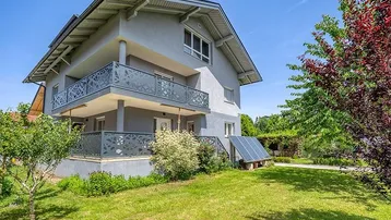 Modernes Einfamilienhaus mit Balkonen, gepflegtem Garten und Photovoltaikanlage auf dem Grundstück.