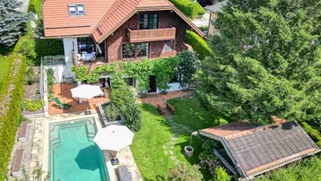 Luftaufnahme eines charmanten Hauses mit großem Garten, privatem Pool und sonnigen Terrassen.