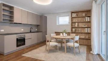 Moderne Küche mit beigen Schränken, Holzboden und integriertem Essbereich.