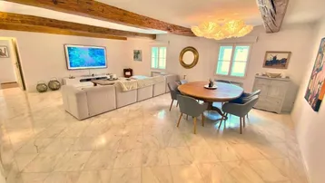 Geräumiger Wohn- und Essbereich mit freiliegenden Holzbalken und elegantem Marmorboden.