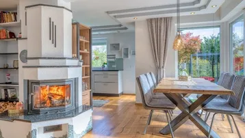 Heller Wohn- und Essbereich mit modernem Kamin, Holzboden und großen Fenstern zum Garten.