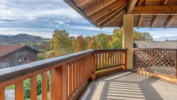 Geräumiger Balkon mit Holzbalken und Fliesenboden bietet einen weiten Blick auf die umliegende Landschaft.