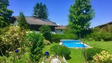 Großer Garten mit Rasenfläche, Swimmingpool und gemütlichem Sitzbereich im Freien.