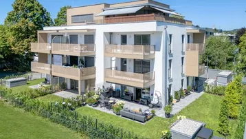 Modernes Mehrfamilienhaus mit mehreren Balkonen, Terrassen und gepflegter Gartenanlage in sonniger Lage.