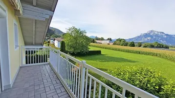 Geräumiger Balkon mit Fliesenboden und weitem Blick über grüne Felder und Berge.