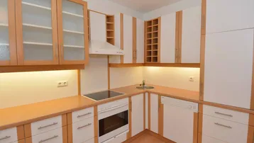 Helle Einbauküche mit hellen Holzfronten, integrierten Geräten und viel Stauraum.