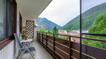Balkon mit Sitzgelegenheiten und weitem Blick auf die umliegenden Berge und die Ortschaft.