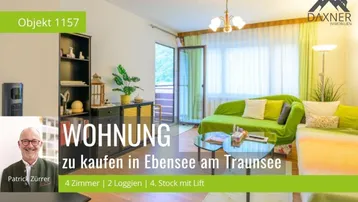 Helles Wohnzimmer mit grünem Sofa, Parkettboden und Zugang zu einem Balkon mit Bergblick.