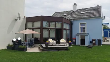 Rückseite des Hauses mit Wintergarten, Terrasse und großem Rasenbereich.