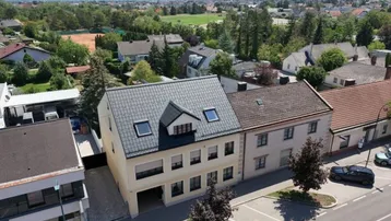 Luftaufnahme des Gebäudes mit umliegender Wohnsiedlung und weitem Blick in die Landschaft.