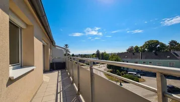 Sonniger Balkon mit weitem Blick über die Dächer und viel Grün in der Umgebung.