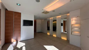 Geräumiger, moderner Gewerberaum mit Holzverkleidung, Spiegelflächen und Einbauregalen, ideal für Empfangsbereich.