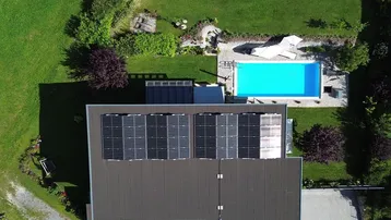 Luftaufnahme des Hauses mit Photovoltaikanlage auf dem Dach und großem Garten mit Pool.