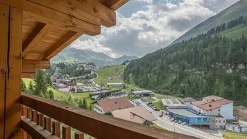 Panoramablick vom Balkon auf die umliegende Berglandschaft und das Tal.