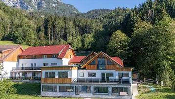 Großzügiger Gebäudekomplex in alpiner Landschaft mit roten Dächern und Blick auf die umliegenden Berge.