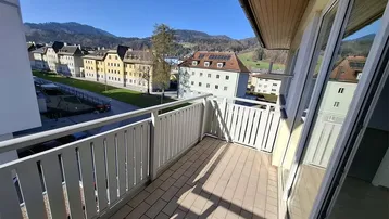 Heller Balkon mit Fliesenboden und Blick auf die umliegende Stadt und Berge.