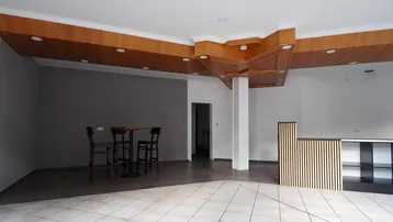 Großer offener Raum mit Fliesenboden, Holzdeckenverkleidung und einer Theke.