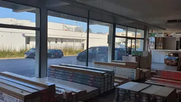 Großer Innenraum eines Geschäfts mit Auslagen von Bodenbelägen und großen Fenstern zur Straße.