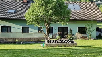 Rückansicht des Hauses mit Garten, Bäumen und Solarpaneelen auf dem Dach.