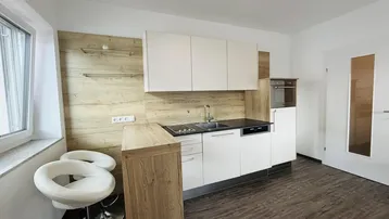 Moderne Küchenzeile mit Holzrückwand, integrierten Geräten, Frühstücksbar und viel Stauraum.