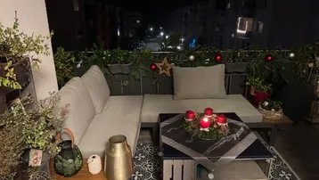 Dekorierter Balkon am Abend mit gemütlicher Sitzecke und festlicher Beleuchtung.