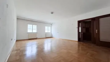 Helles, leeres Wohnzimmer mit Parkettboden und weißen Wänden, bereit zur individuellen Gestaltung.