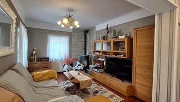 Gemütliches Wohnzimmer mit Holzmöbeln, Kaminofen und gestreiften Tapeten.