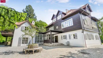 Charmantes Anwesen mit Haupthaus und Nebengebäude, verbunden durch eine verglaste Veranda, umgeben von Natur.